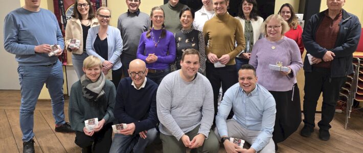 21.01.2026 | Deutscher Clubwettbewerb in der Kölner Sprechbar Etwa sechzehn Mitglieder der Kölner Sprechbar stehen und knien mit ihren Urkunden zusammen für ein Gruppenfoto im Clubraum.