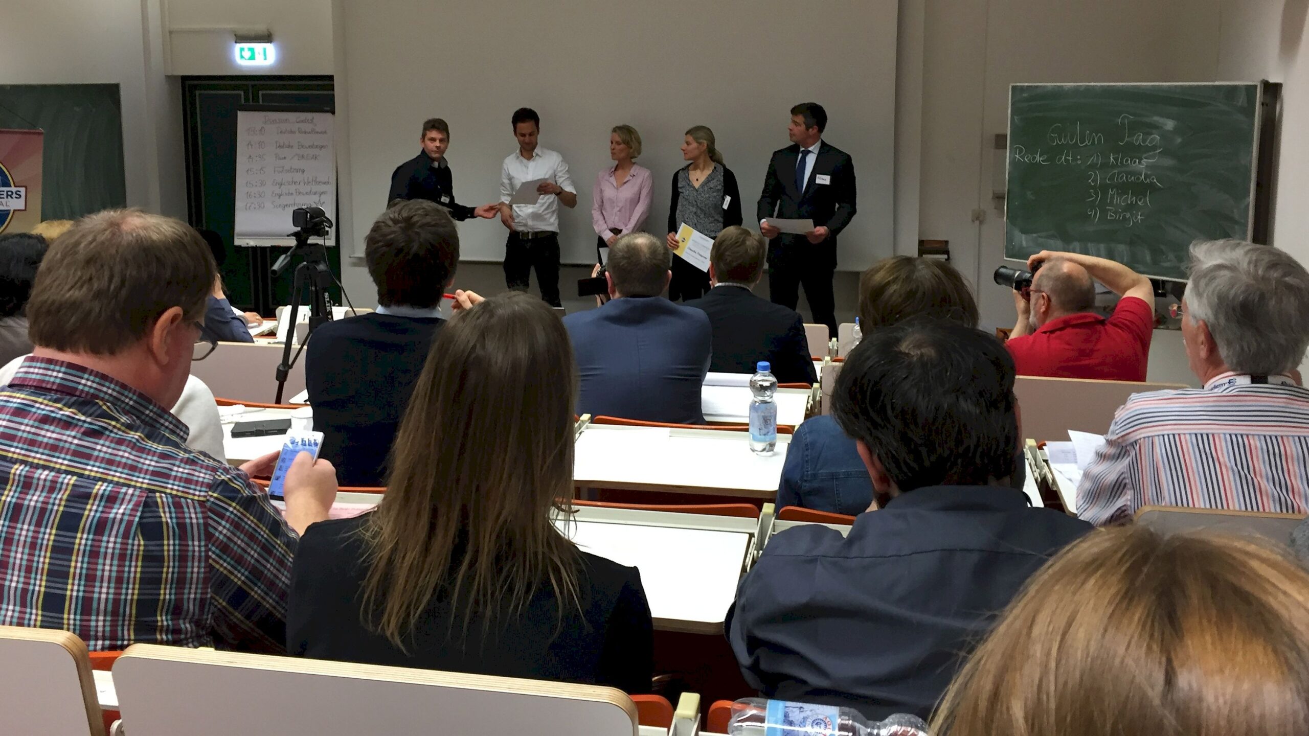 Teilnehmer und Publikum beim Toastmasters Division-Wettbewerb D95A am 16.04.2016 in Köln – Redner auf der Bühne vor vollem Saal.