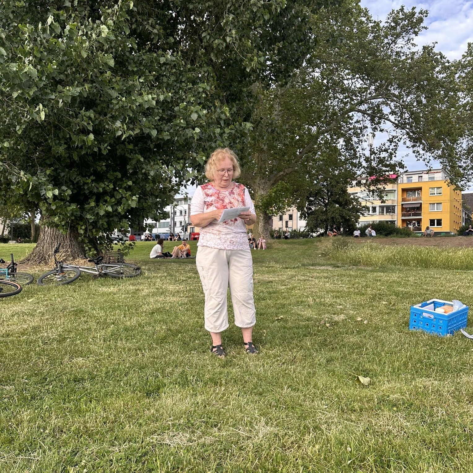 Ein Mitglied der Kölner Sprechbar liest beim Draußen-Meeting auf einer Wiese aus ihren Unterlagen vor.