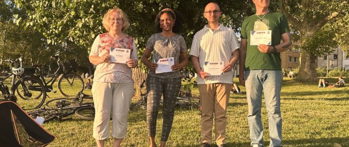 Rückblick: Draußen-Meeting der Kölner Sprechbar am 17.06.2026 Vier Mitglieder der Kölner Sprechbar präsentieren beim Draußen-Meeting am Rheinufer ihre Urkunden.