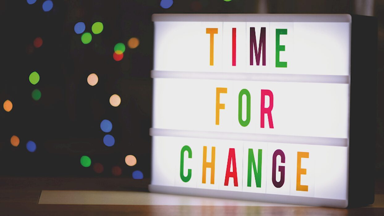 Eine beleuchtete Buchstabenbox zeigt bunt die Worte „Time for Change“, im dunklen Hintergrund funkeln unscharfe Lichter.