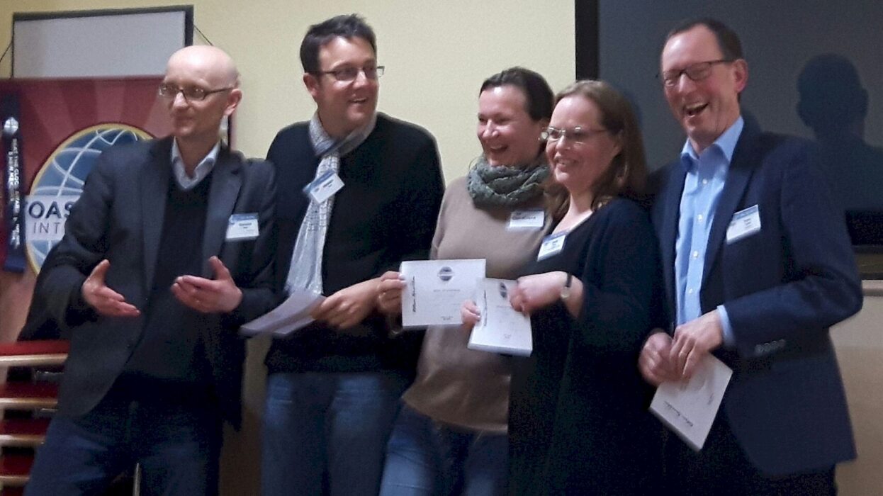 Mitglieder der Kölner Sprechbar lachen mit Urkunden in der Hand vor dem Toastmasters-Banner beim Clubabend am 10.02.2016.