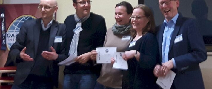 10.02.2016 – „Goethe war gut, Mann, konnte der reimen“ Mitglieder der Kölner Sprechbar lachen mit Urkunden in der Hand vor dem Toastmasters-Banner beim Clubabend am 10.02.2016.