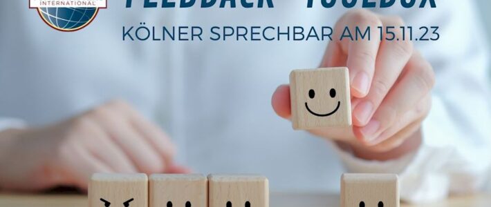 Grafik „Feedback-Toolbox“ mit einer Hand, die einen lächelnden Holzwürfel aus einer Reihe von Würfeln mit unterschiedlichen Gesichtsausdrücken auswählt, dazu das Toastmasters-International-Logo.