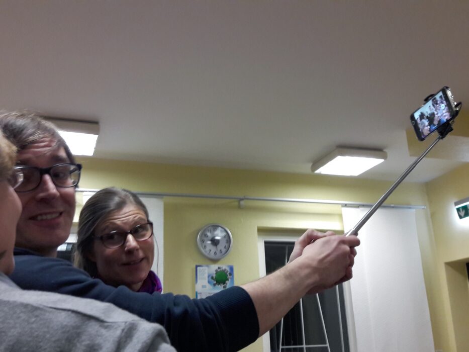 Mitglieder der Kölner Sprechbar machen ein Gruppen-Selfie mit einem Selfie-Stick.