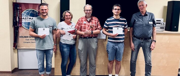 Fünf lächelnde Toastmasters-Mitglieder stehen nebeneinander, drei von ihnen halten ihre Auszeichnungsurkunden in den Händen.