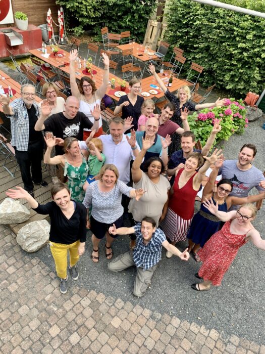 Große Gruppe steht bei der Jubiläumsfeier im Garten des Bürgerzentrums zusammen.