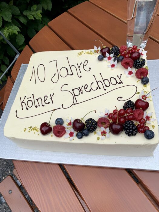 Jubiläumstorte mit der Aufschrift 10 Jahre Kölner Sprechbar steht auf einem Tisch.