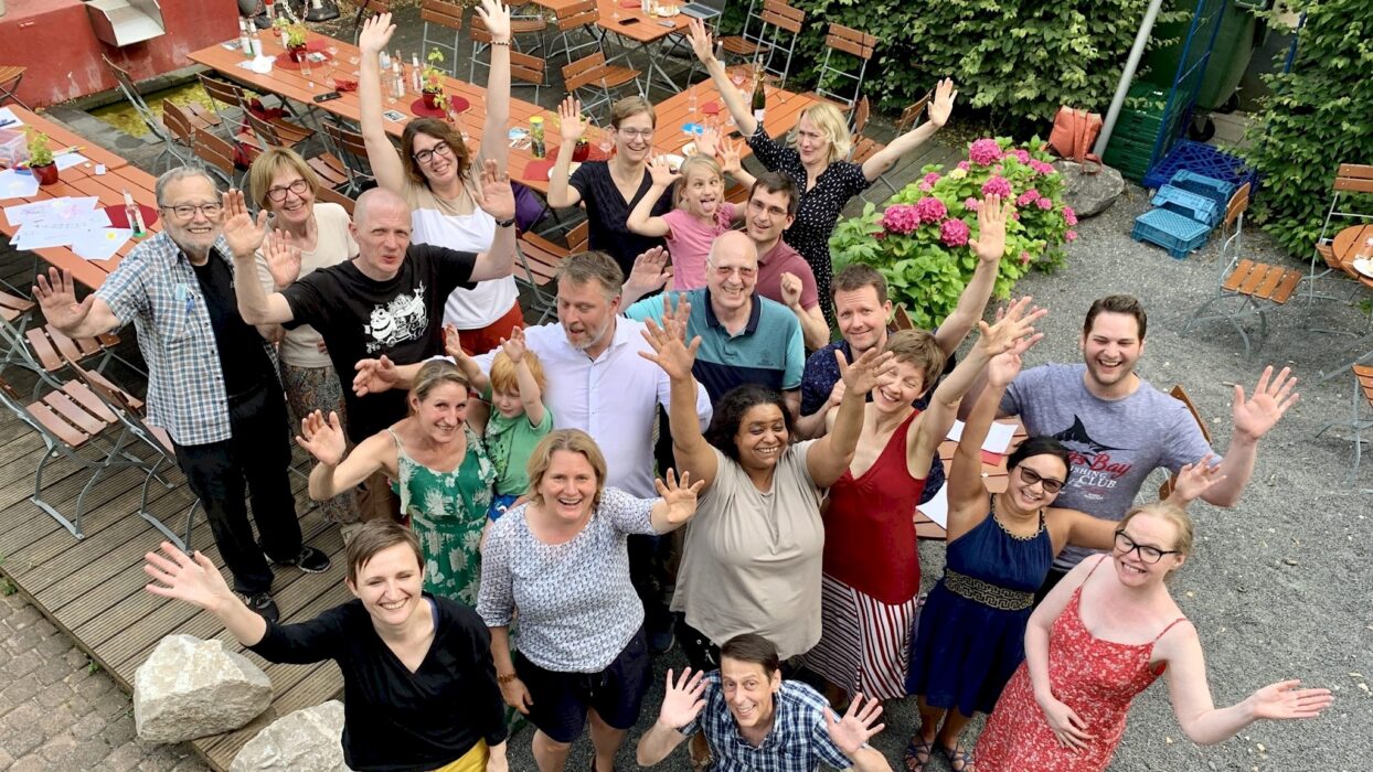 Mitglieder, Familien und Freunde winken bei der Jubiläumsfeier im Garten des Bürgerzentrums in die Kamera.