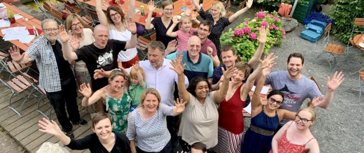 Mitglieder, Familien und Freunde winken bei der Jubiläumsfeier im Garten des Bürgerzentrums in die Kamera.