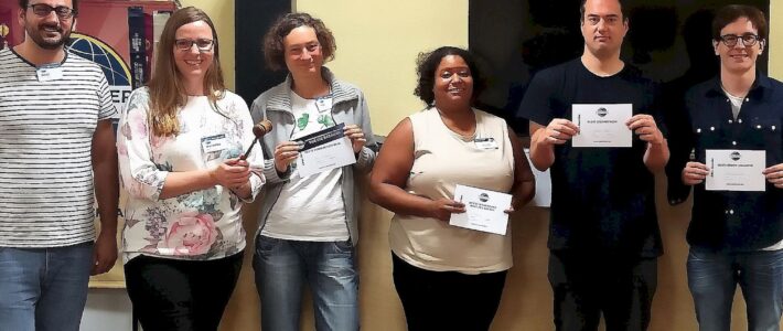 Sechs Teilnehmende stehen mit Urkunden und Hammer vor dem Toastmasters-Banner.