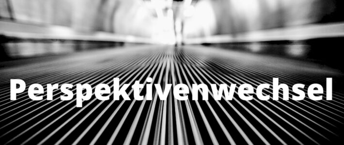 Schwarz-weiße Linien laufen perspektivisch auf eine Person und den Schriftzug Perspektivenwechsel zu.