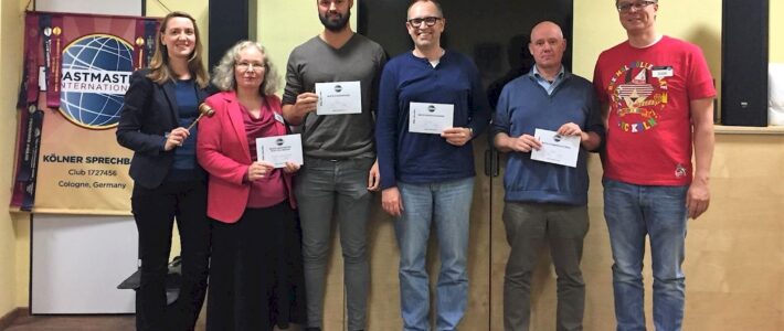 Sechs Teilnehmende stehen mit Urkunden und Hammer vor dem Toastmasters-Banner.