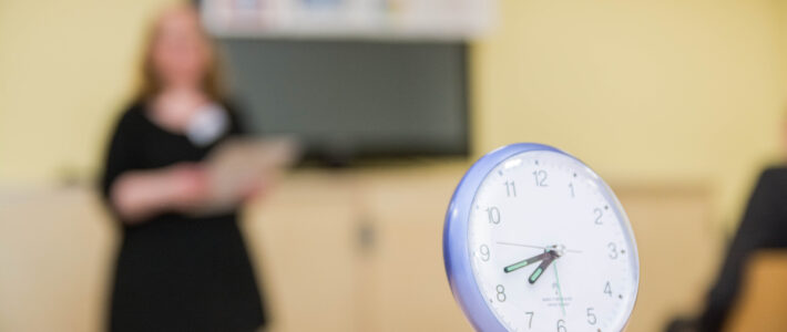 Zeitmess-Uhr für Redezeiten im Vordergrund, Rednerin im Hintergrund bei einem Clubabend der Kölner Sprechbar