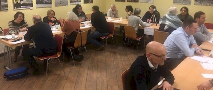 Teilnehmende eines Living-Library-Abends sitzen sich in kleinen Gesprächsgruppen an mehreren Tischen gegenüber.