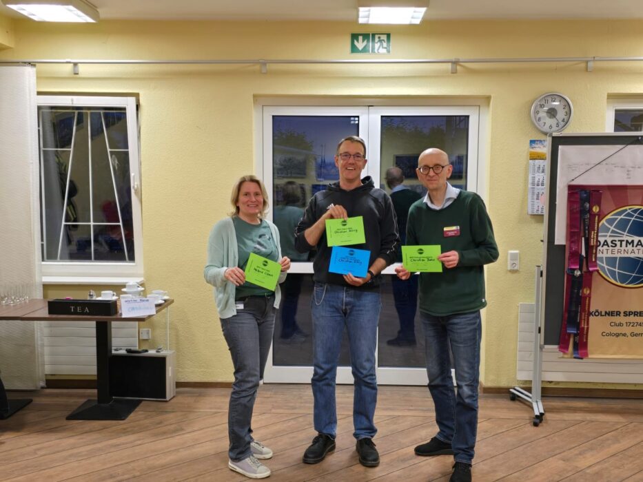 Drei Preisträger des Abends mit Urkunden vor dem Toastmasters-Banner
