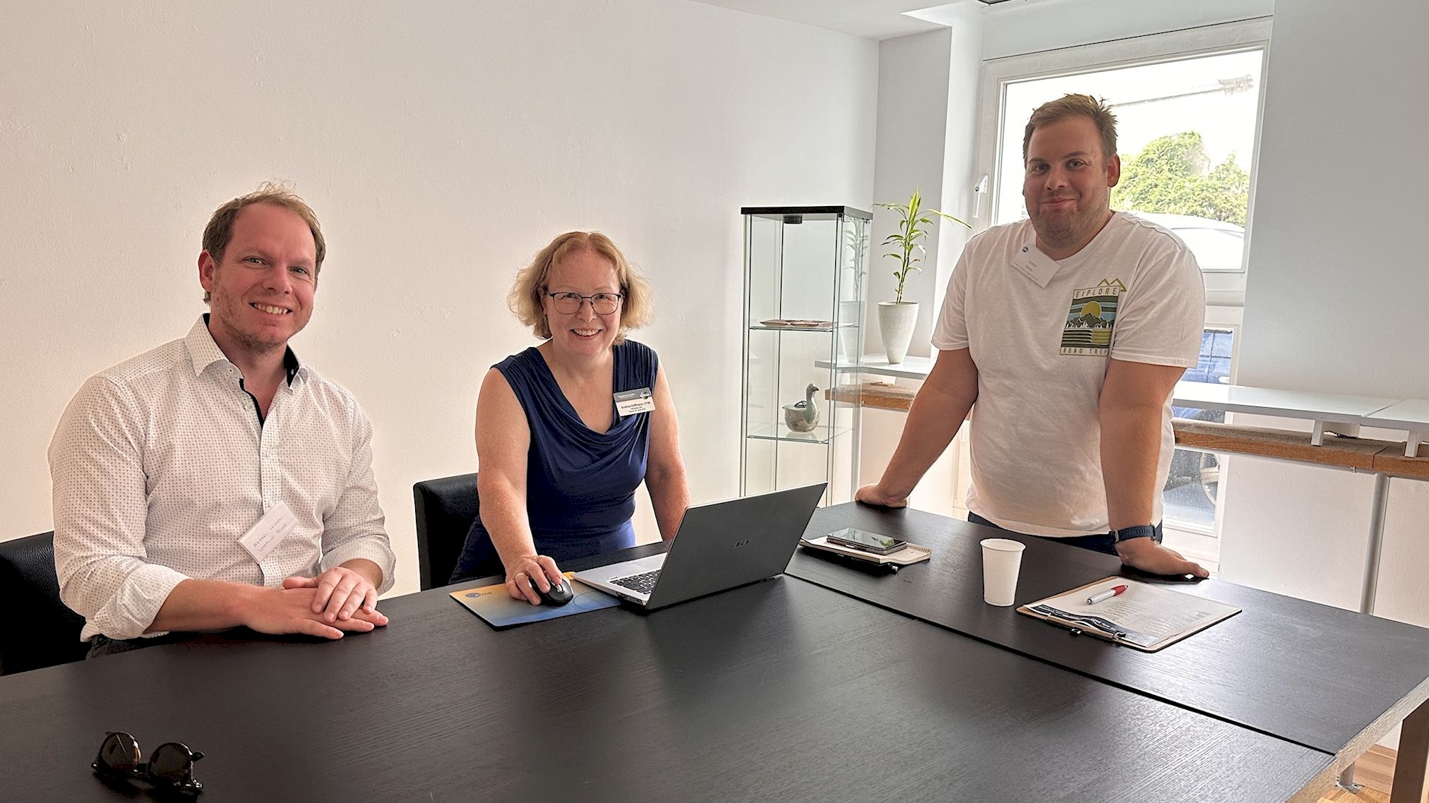 Michael Levardi, Andrea Hoffmann und Kristof Glienke sitzen und stehen gemeinsam an einem Tisch beim Club Officer Training.