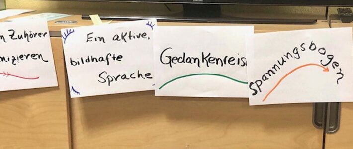 Was ist die Quintessenz? Beschriftete Papierstreifen zu Rhetorik und Redestruktur liegen auf einer braunen Fläche.