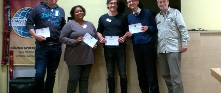 We want to say something, but how? Fünf Mitglieder der Kölner Sprechbar mit Urkunden vor dem Toastmasters-Banner.