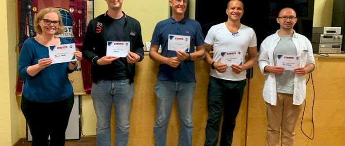 Fünf Mitglieder der Kölner Sprechbar stehen mit ihren Urkunden vor dem Toastmasters-Banner.